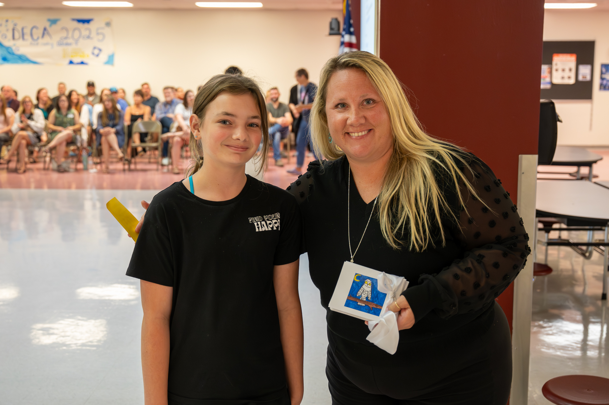 A board of education member standing proudly with a student, who gifted them artwork.